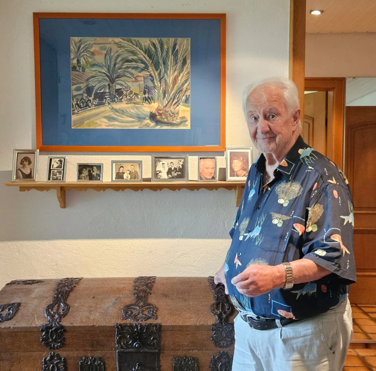 Abbildung: Roland Krüppel in seinem Haus vor einem Aquarell von Carl Rabus